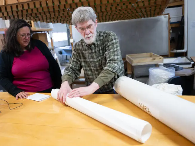 Tim Barrett, the former director of the University of Iowa Center for the Book, rolls a sheet of paper next to Sara Langworthy, the center's current director.